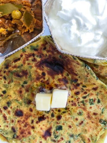 Palak parantha with butter pickle and bowl of yogurt
