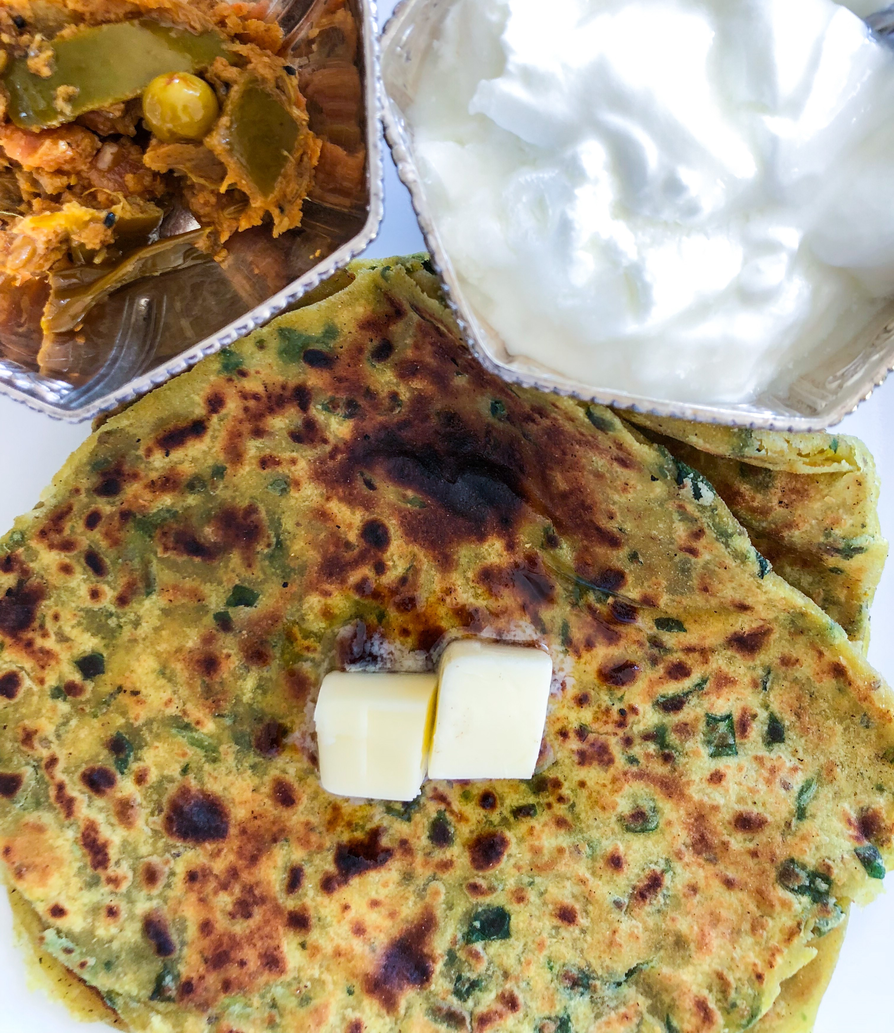 Palak parantha with butter pickle and bowl of yogurt