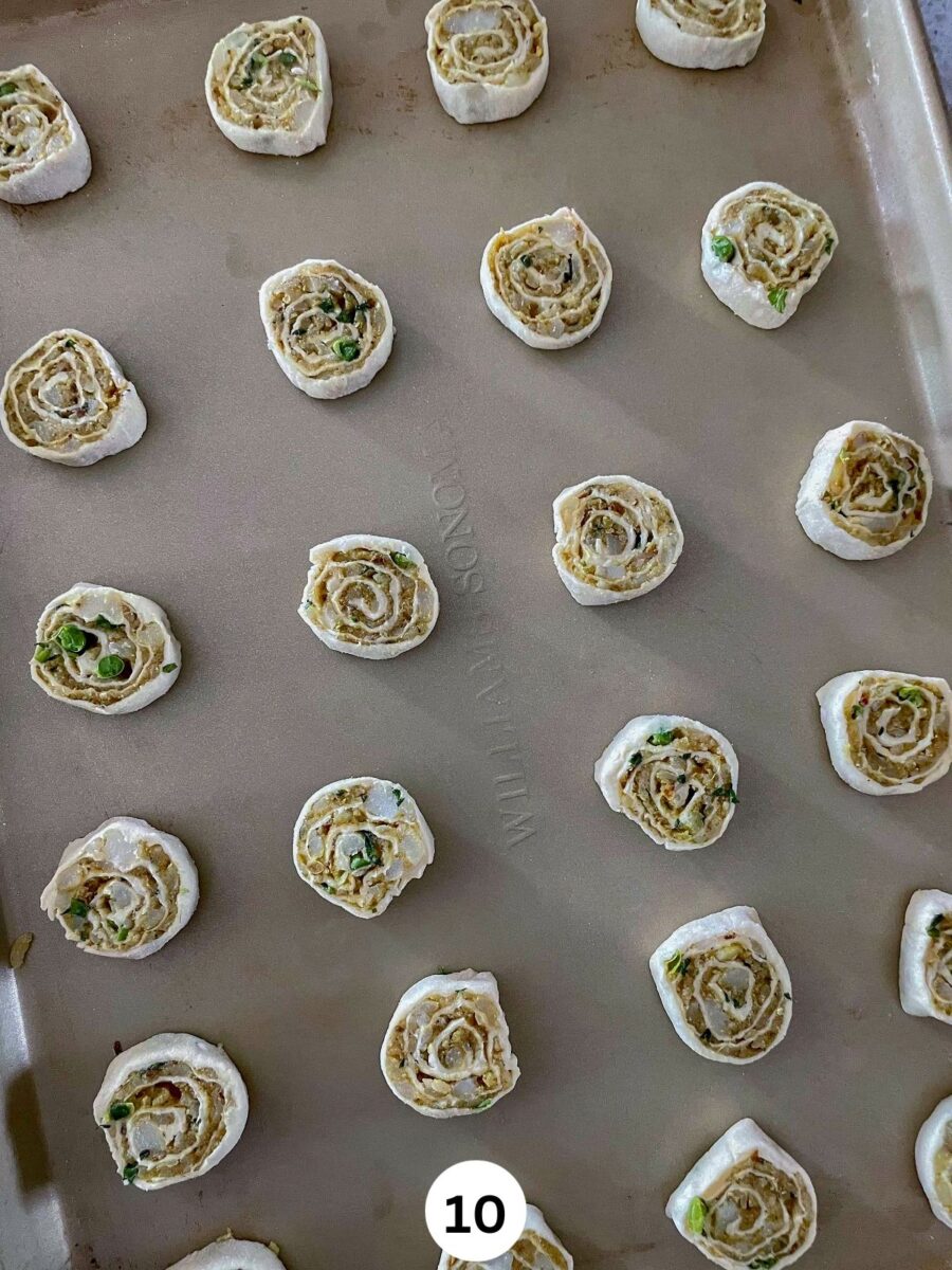 Samosa appetizer pinwheel slices on a cookie sheet ready to be baked.