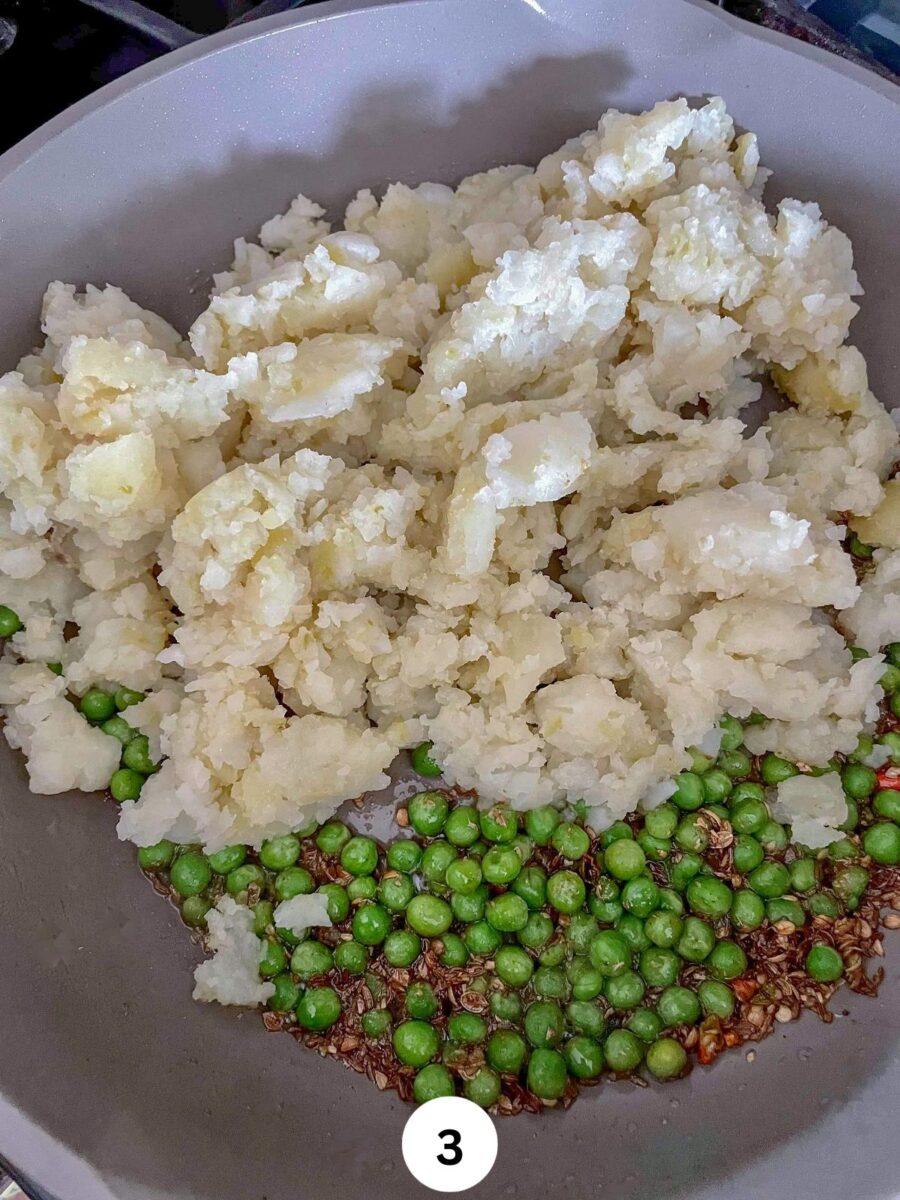 Boiled, mashed potatoes and green peas with oil in a non stick pan.