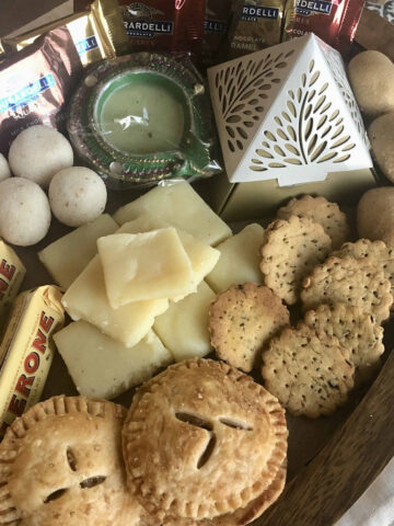 Diwali desserts and snacks served on a wooden tray.