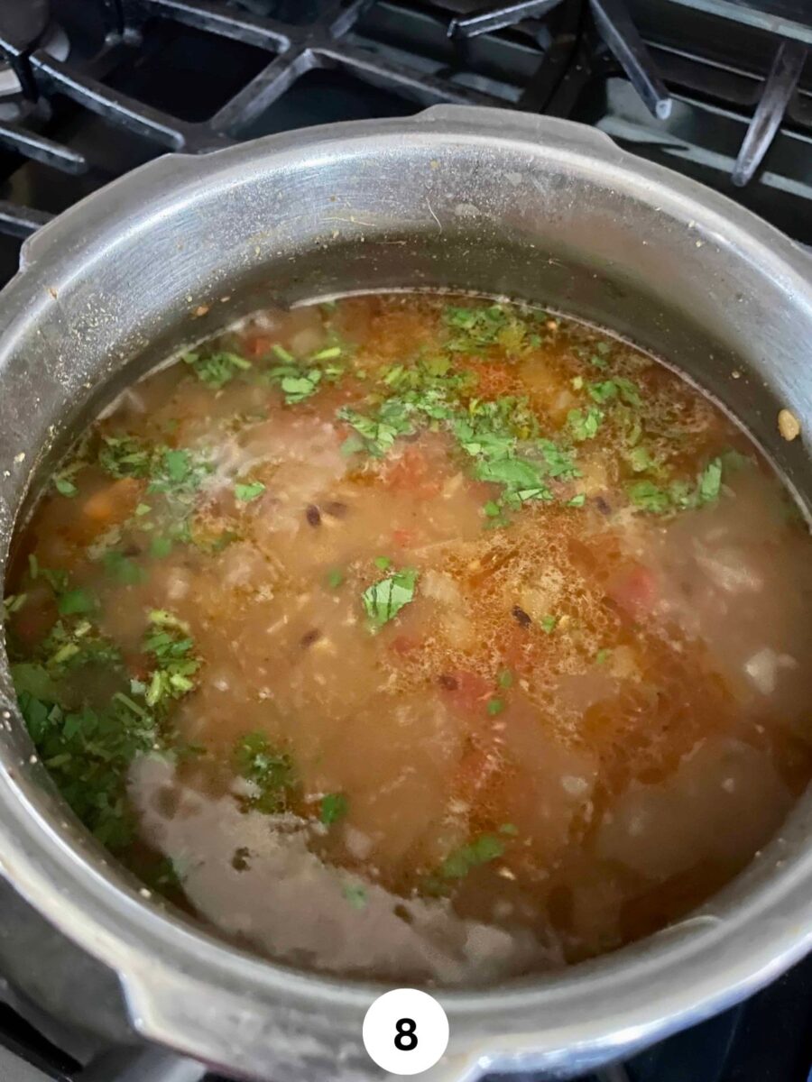 Step 8 of Lentil Dal recipe showing finished dal with a sprinkle of garam masala and chopped cilantro in a stainless steel pressure cooker pot.