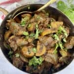 Butter Garlic Mushrooms in a steel serving dish garnished with chopped cilantro.