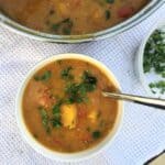 Curried butternut squash and lentil soup in a white ceramic bowl with a spoon.