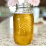 Melted ghee in a mason jar on a counter.
