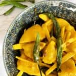 Galgal ka achar or lemon ginger and green chili pickle in a grey ceramic bowl on a white marble background.