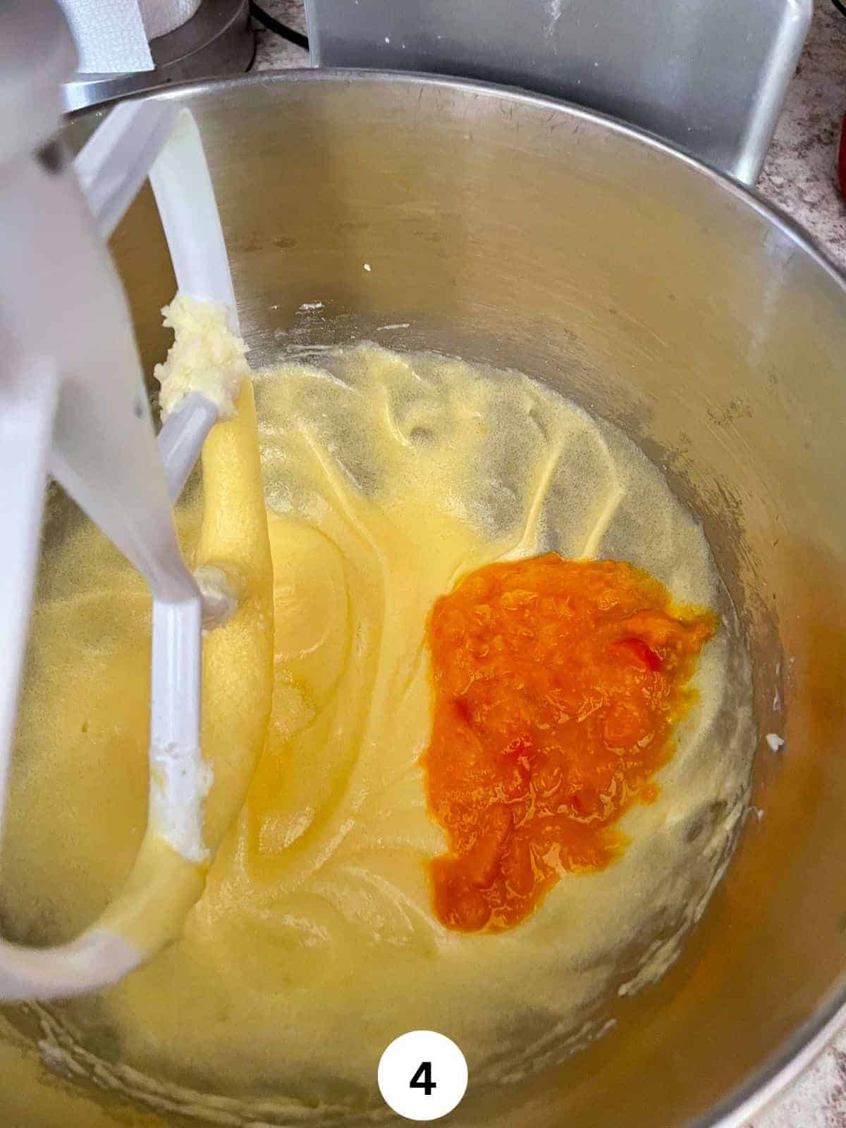 Pureed oranges added to butter, sugar and egg mixture in the stainless steel bowl of a stand mixer fitted with paddle attachment,