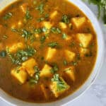 Matar Paneer Curry garnished with chopped cilantro in a white ceramic bowl on a white marble background.