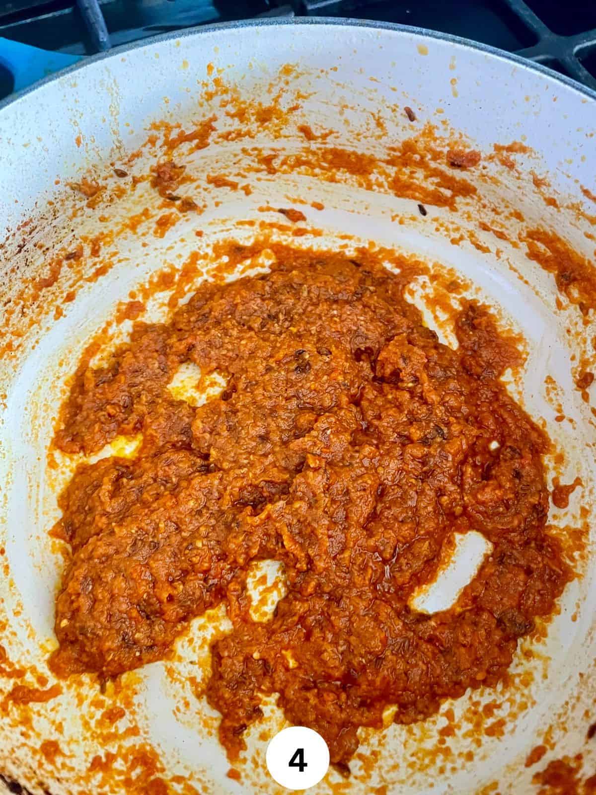 Masala of onion, tomatoes, ginger, garlic, and green chili cooked down with spices and oil in a ceramic pot.