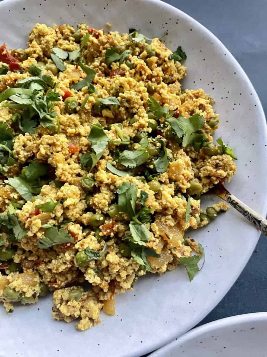 Paneer Bhurji garnished with chopped cilantro served in a speckled white ceramic bowl.