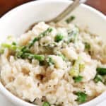 Close up of No-stir spring risotto with asparagus and peas in a white bowl, made in pressure cooker