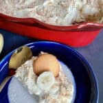 Banana pudding with a vanilla wafer on top in a blue and white ceramic plate on a blue background.
