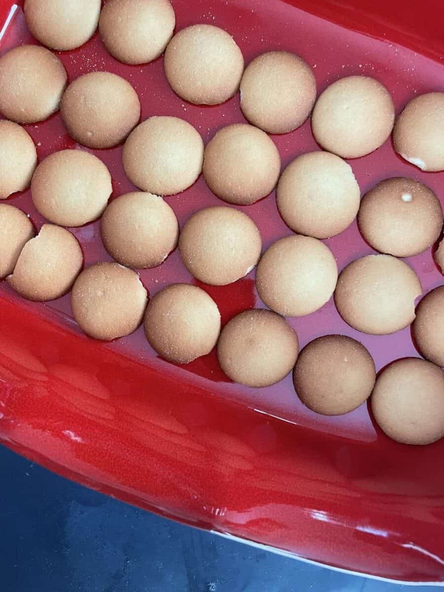 A layer of vanilla wafers in a red ceramic dish.
