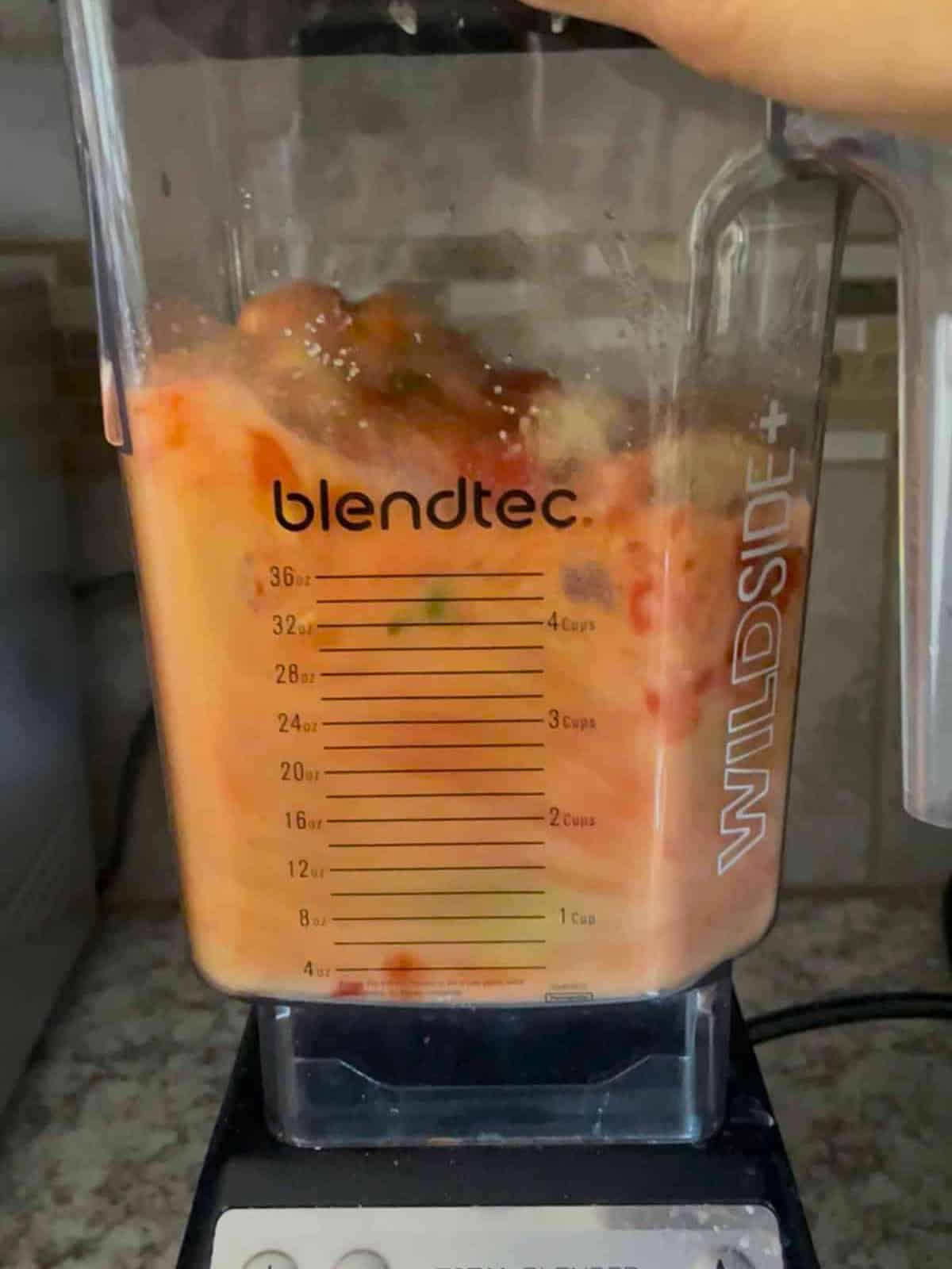 A blender with gazpacho being blended in it on a counter.