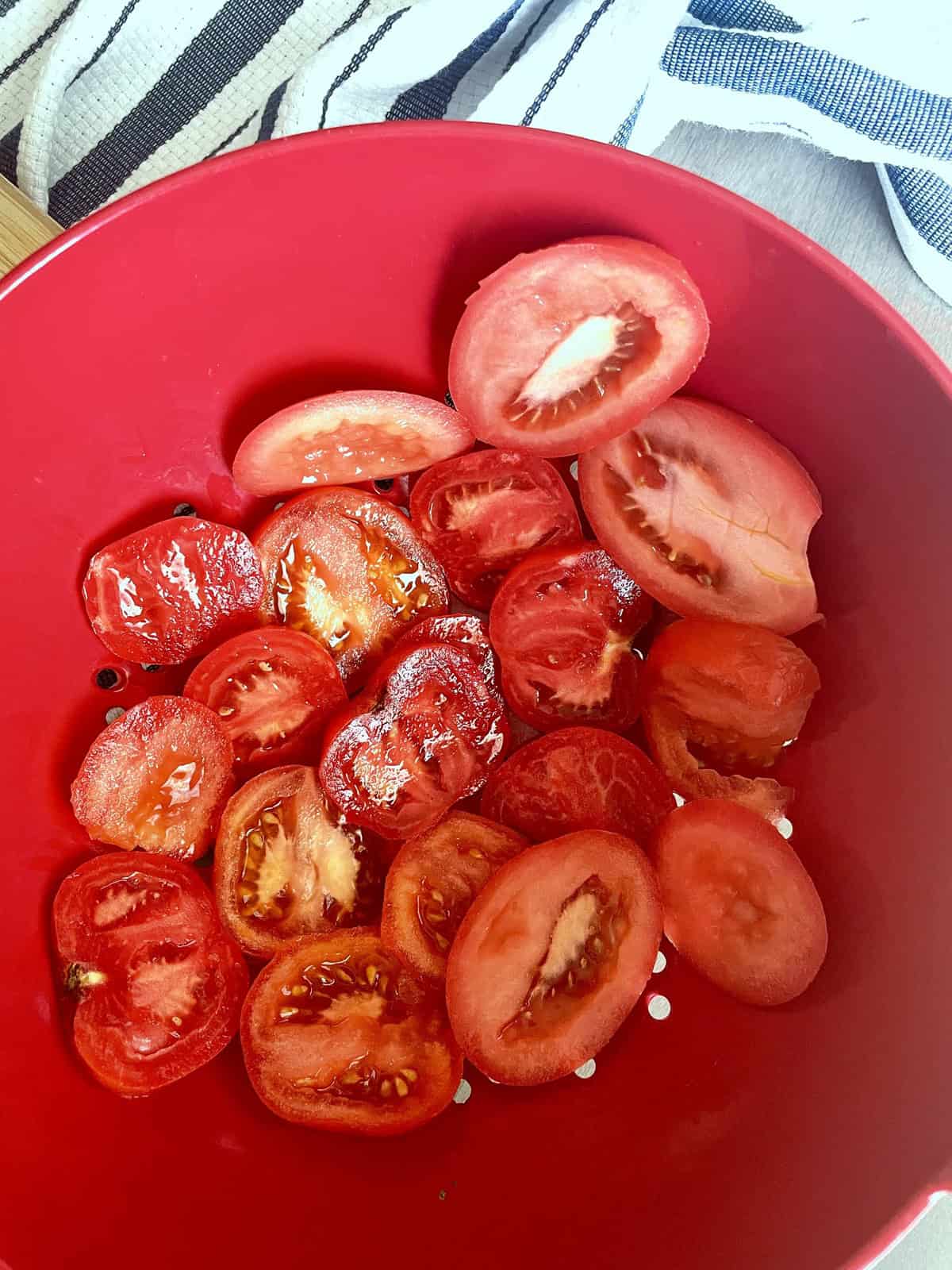 Sliced tomatoes in a red colander.