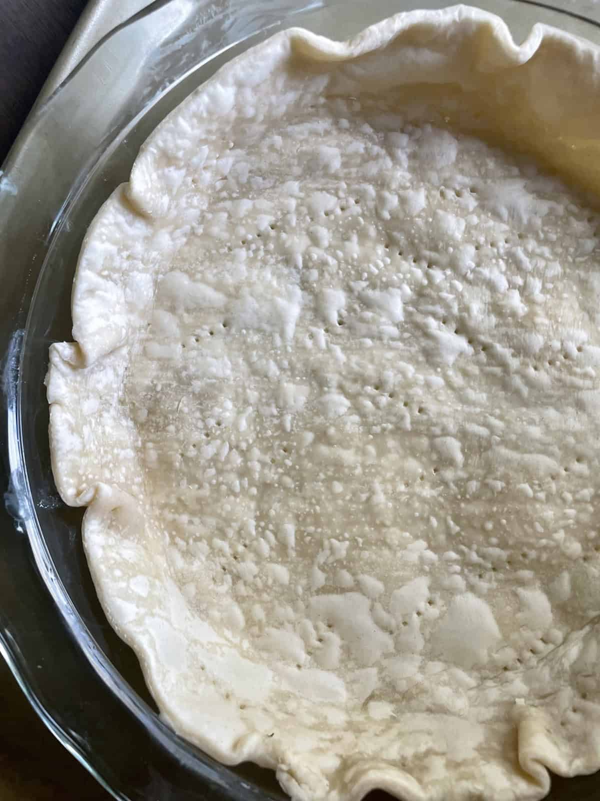 A glass pie dish with baked pie crust.
