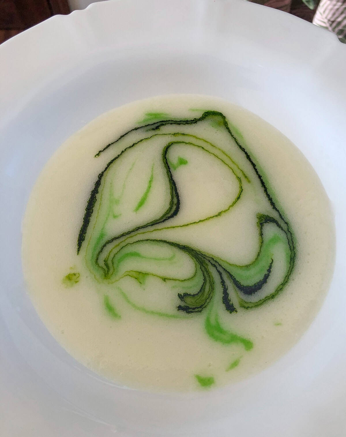Sugar glaze with green swirls in a white ceramic bowl. The glaze is for glazing star-shaped cutout lemon sugar cookies.