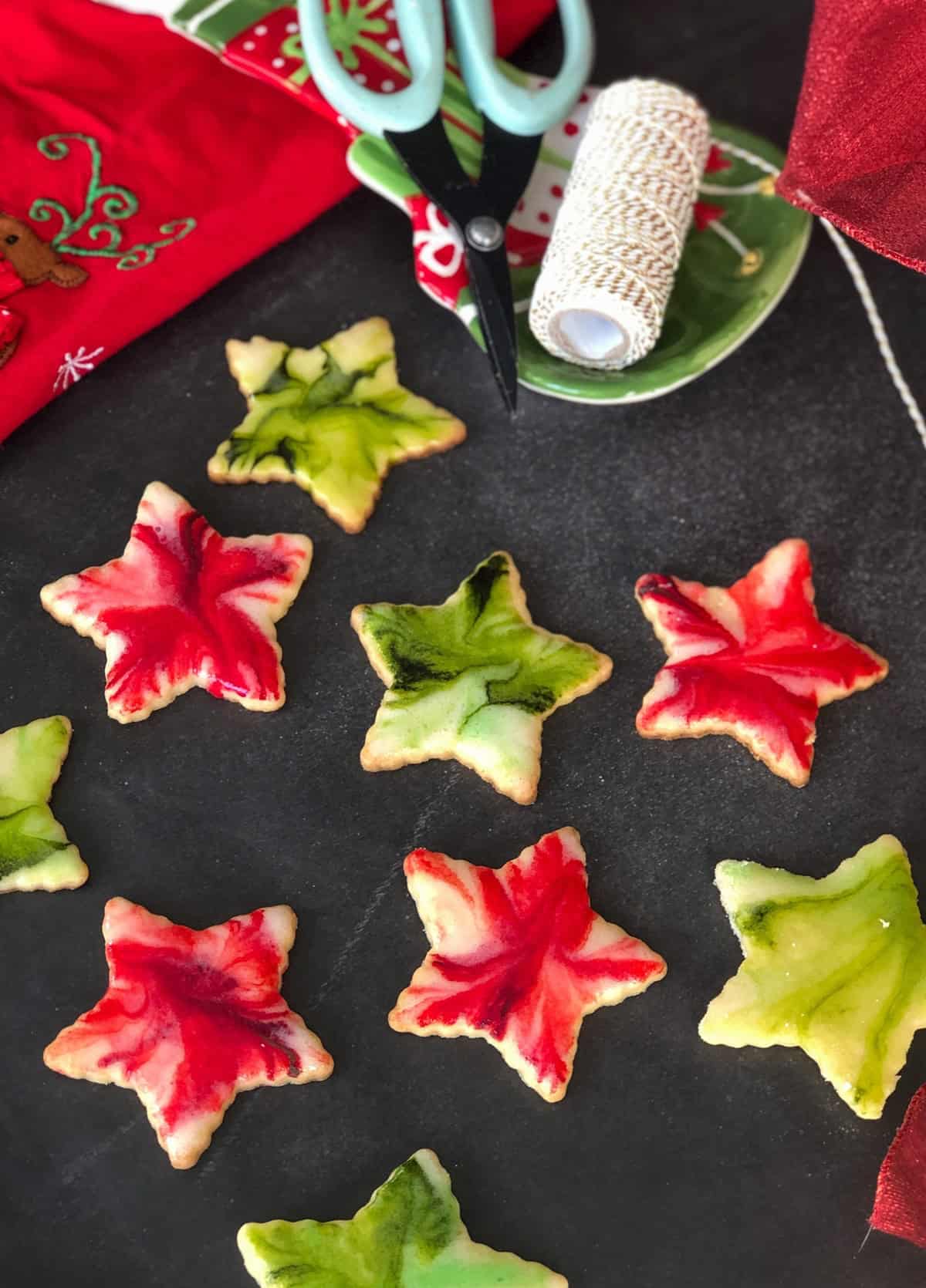 Star-shaped cutout lemon sugar cookies with red, green, and white glaze on a black background.