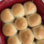 Rows of baked dinner rolls in a red ceramic baking dish.