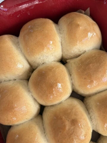 Baked dinner rolls in a red ceramic baking dish.