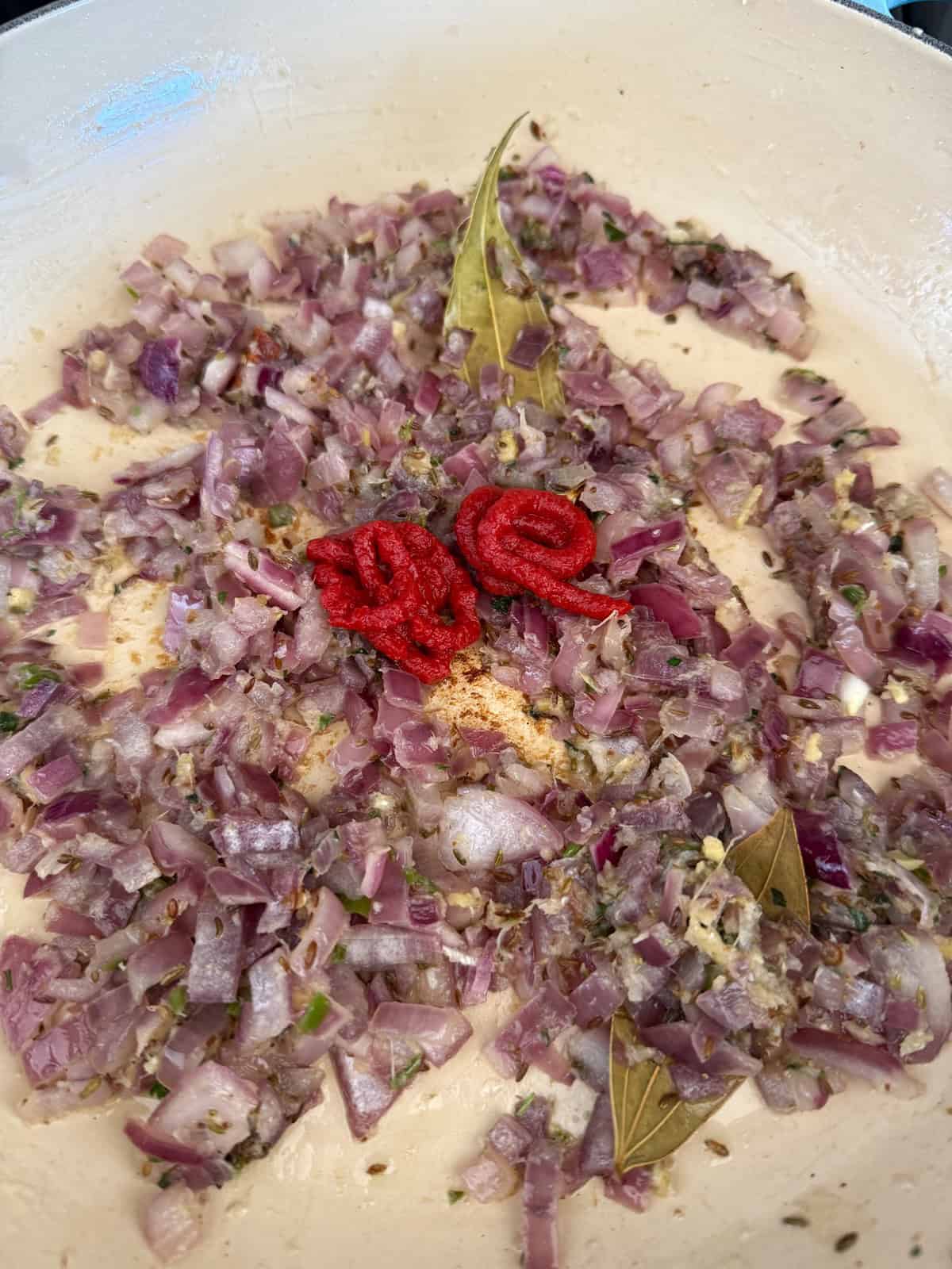Chopped onions cooking in a pan with tomato paste.