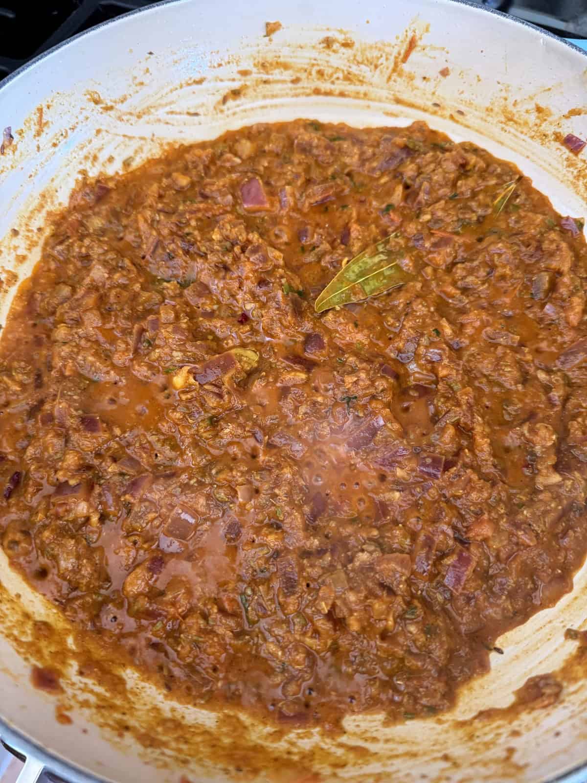 A masala of onion and tomato with spices cooking in a pan.