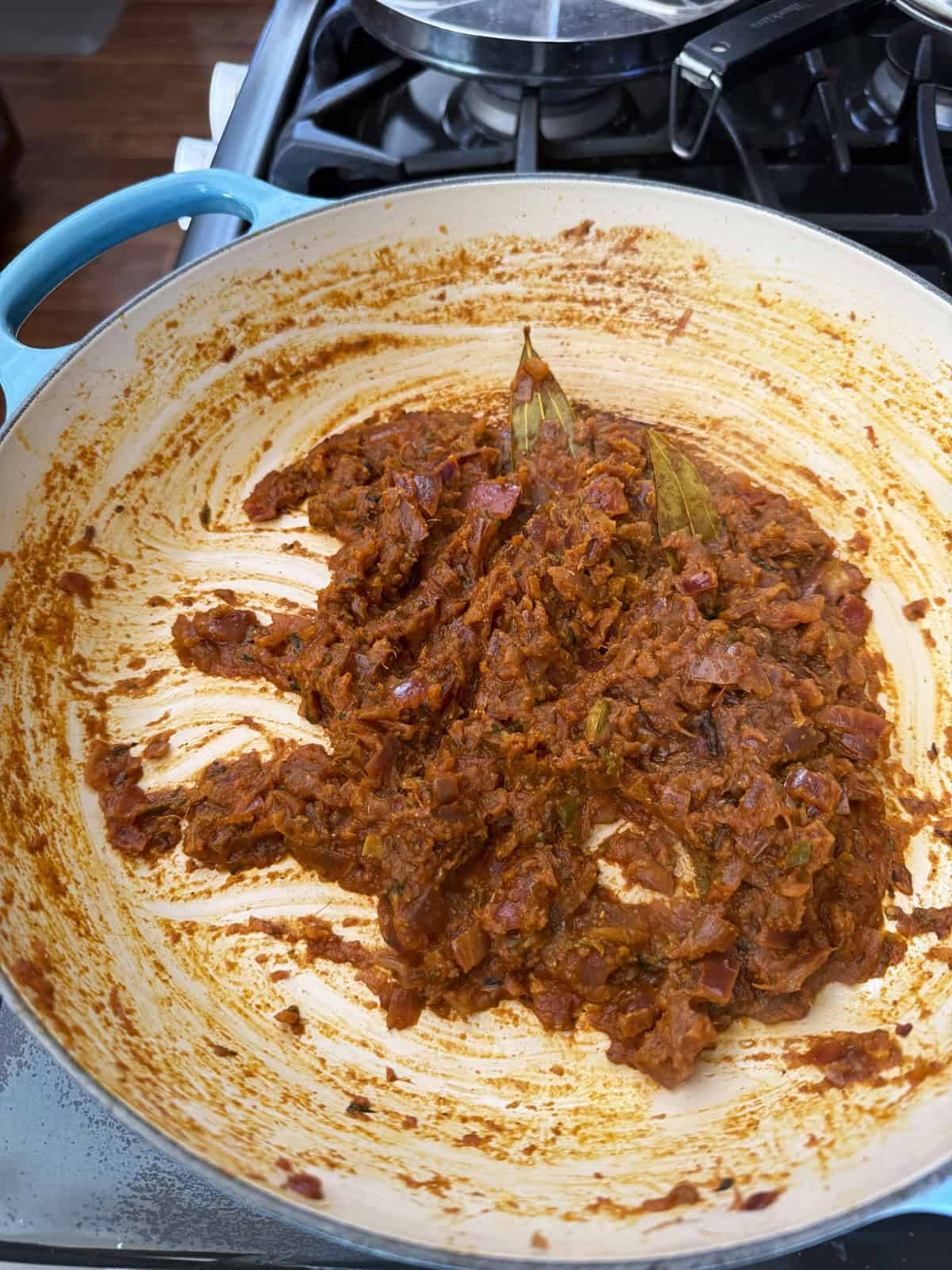 A masala of onion and tomato with spices cooking in a pan.