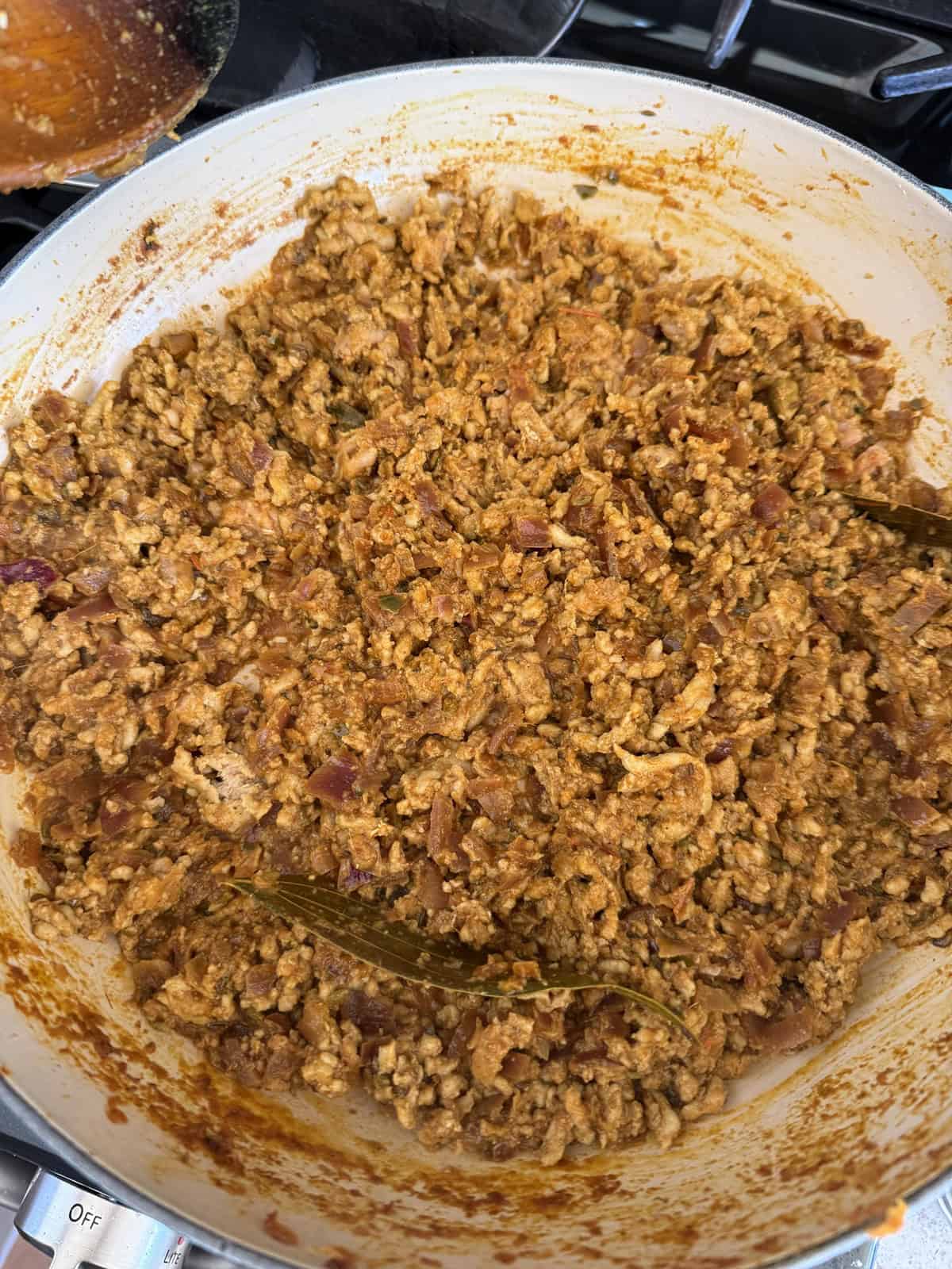 Ground meat curry in a pan with a bay leaf.