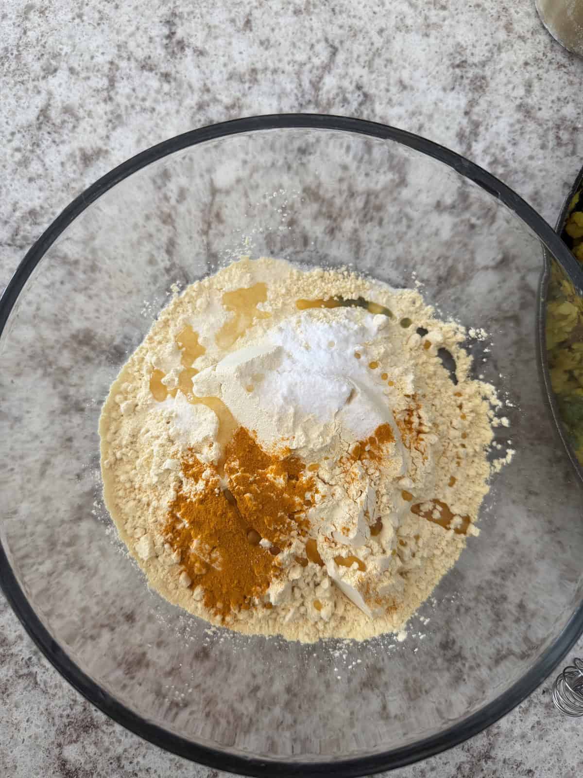 Chickpea flour with spices in a glass bowl.