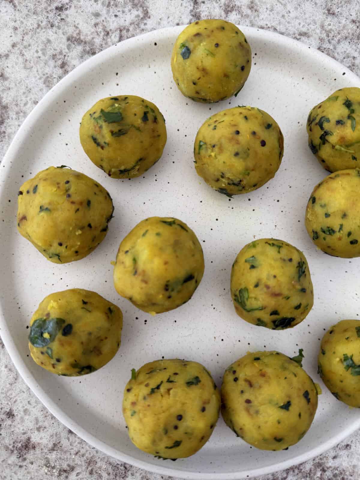 Delicious mini spiced mashed potato balls on a white plate.