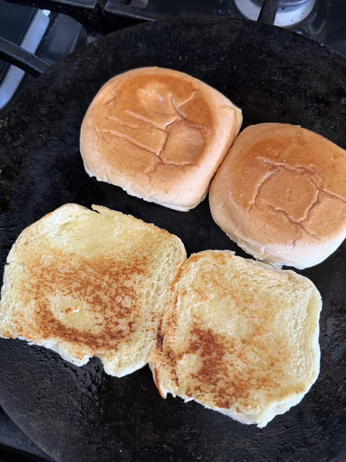 Buttered and toasted dinner rolls in a cast iron skillet.