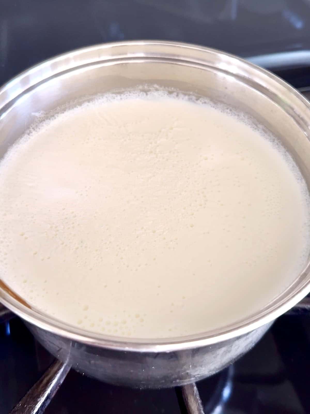 Heating up milk in a stainless steel saucepan to make homemade dahi or Indian yogurt.