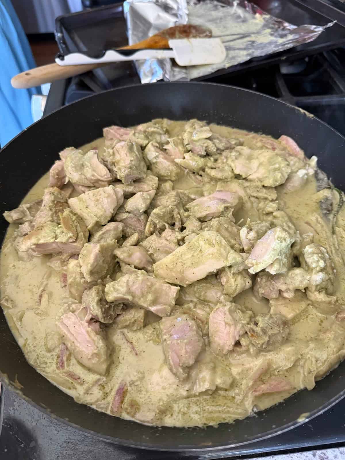 Sautéed chicken pieces in an Afghan chicken sauce on a stovetop.