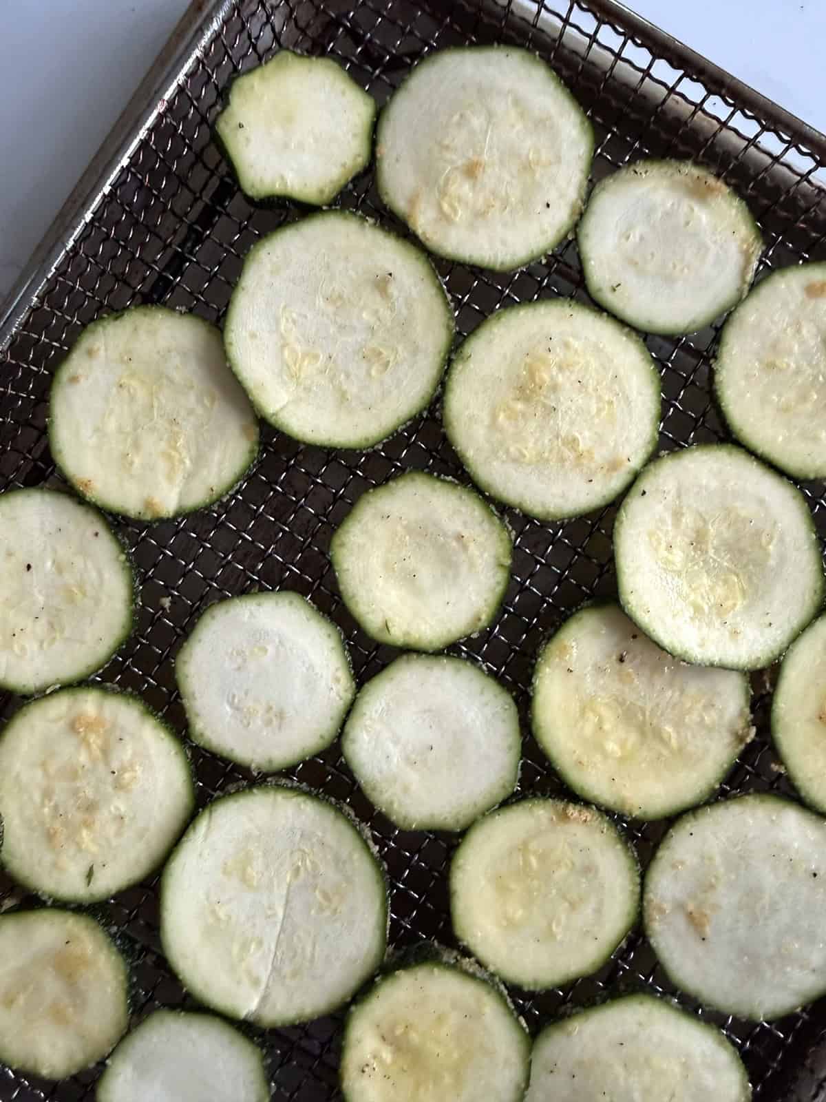 Zucchini slices on an air fryer tray for a crispy air-fried zucchini recipe.