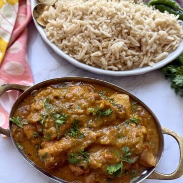 Easy weeknight punjabi chicken curry in a pot with rice on a white marble background.