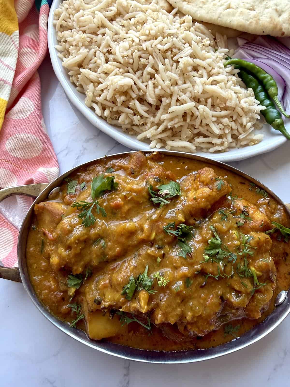 Easy weeknight punjabi chicken curry in a pot with rice on a white marble background.
