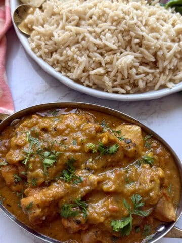 Easy weeknight punjabi chicken curry in a pot with rice on a white marble background.