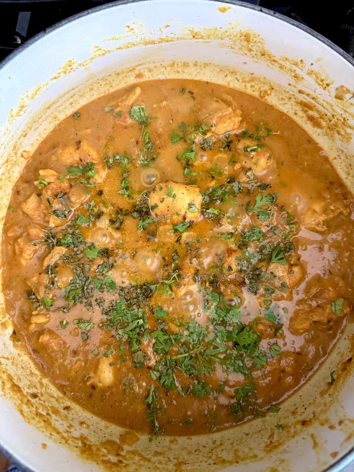 Easy weeknight punjabi chicken curry in an enameled cast iron pot garnished with cilantro.