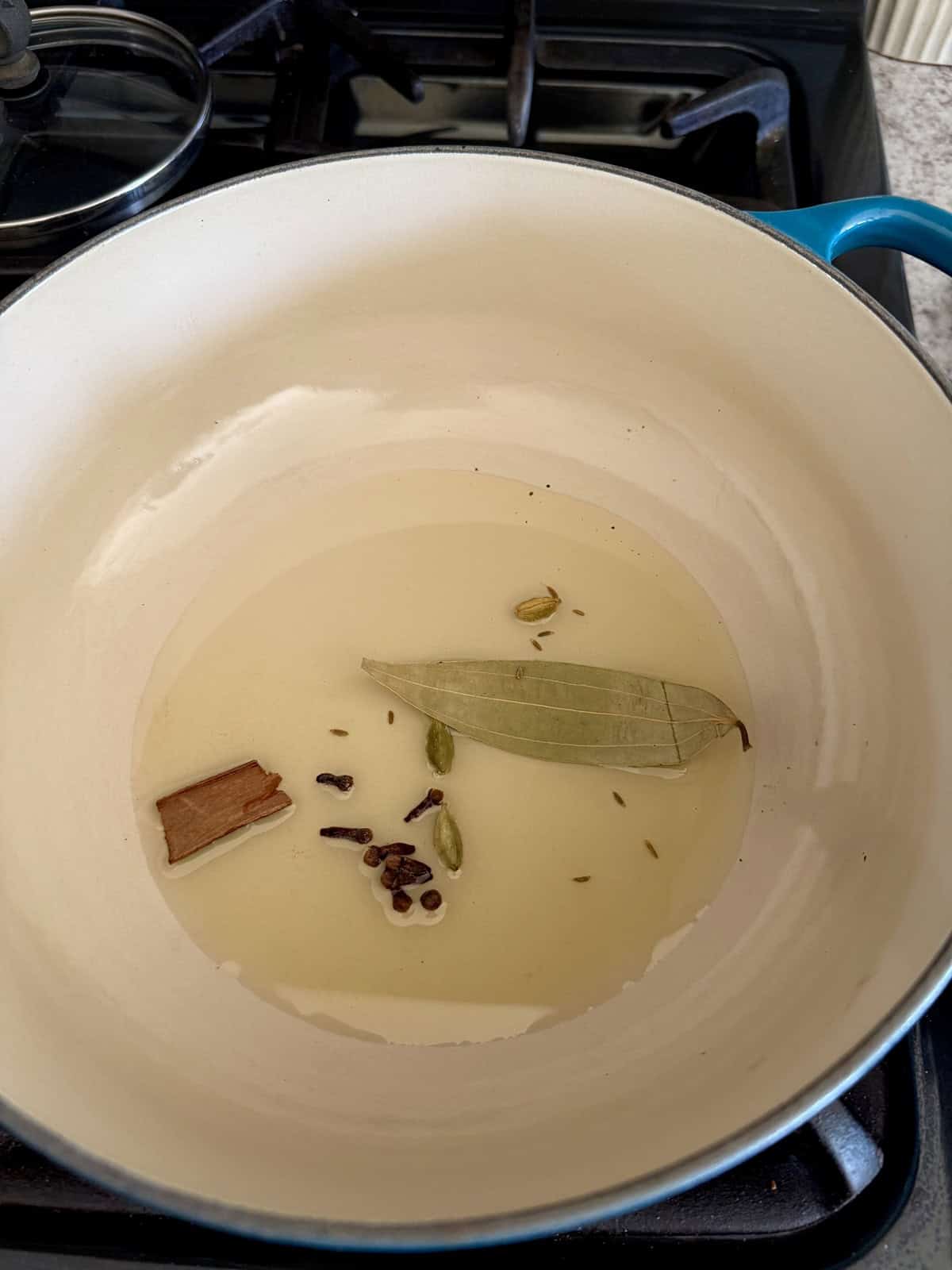 Whole spices in oil in an enameled cast iron pot.