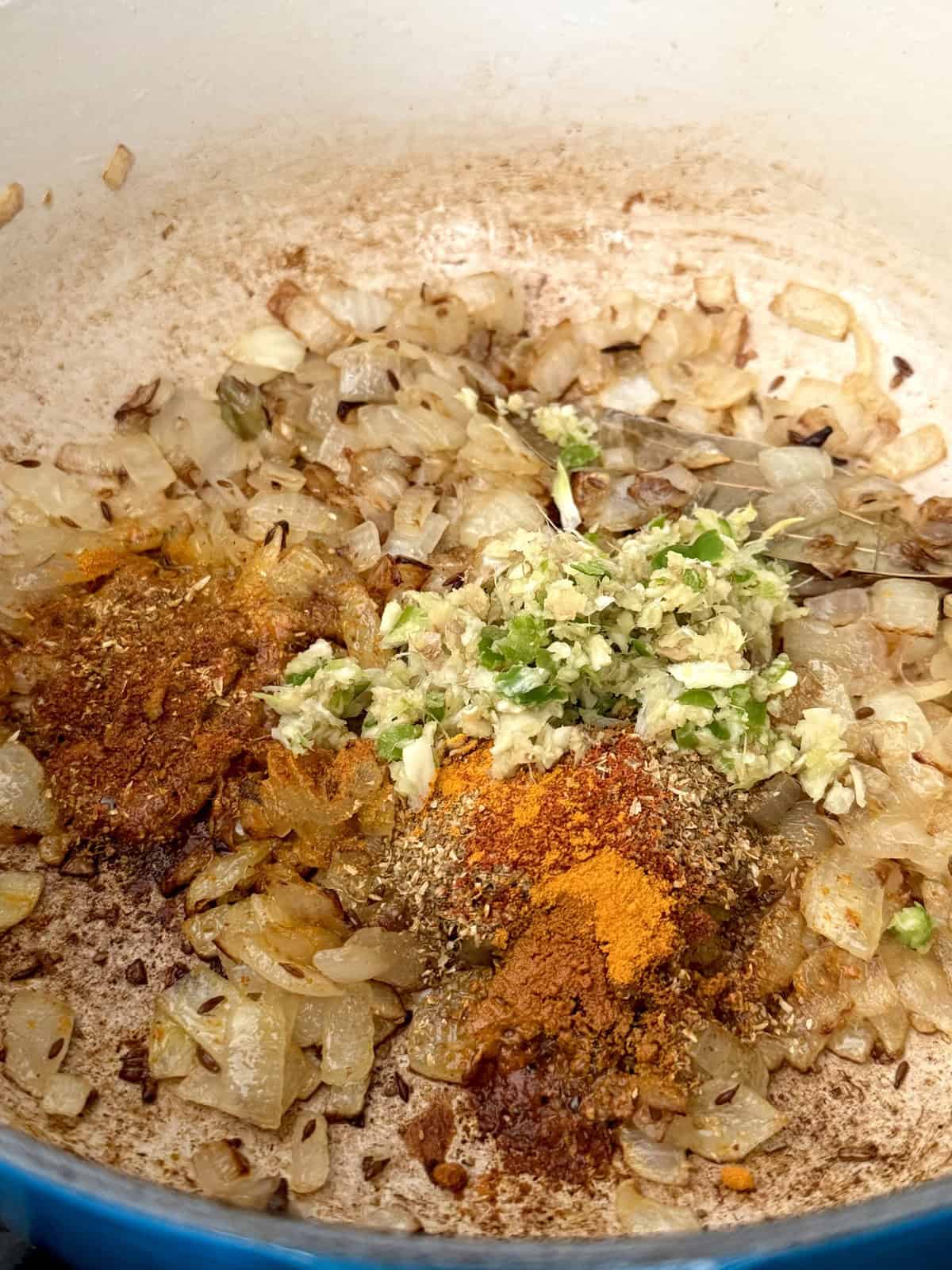 Sauteed chopped onions with spices and ginger garlic and green chili paste in an enameled cast iron pot.
