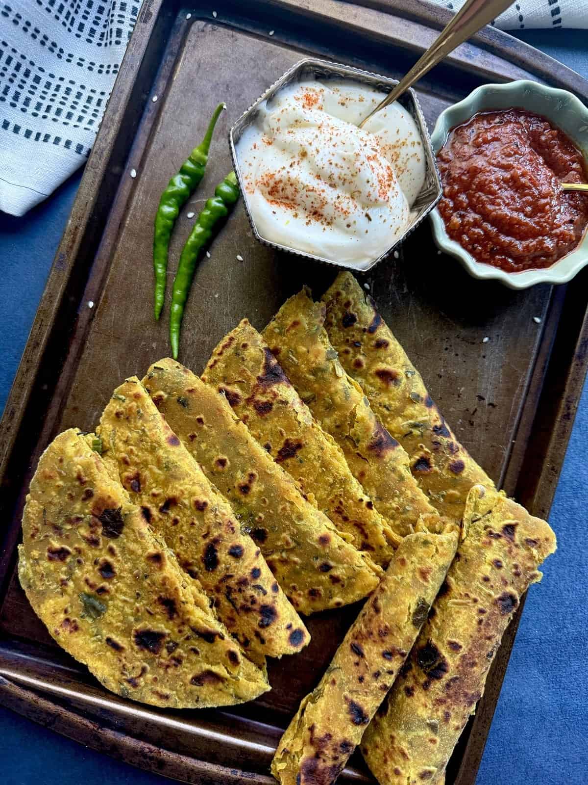 Indian high protein tofu thepla (flatbread) with spicy tomato chutney, yogurt, and green chilies on a dark surface.