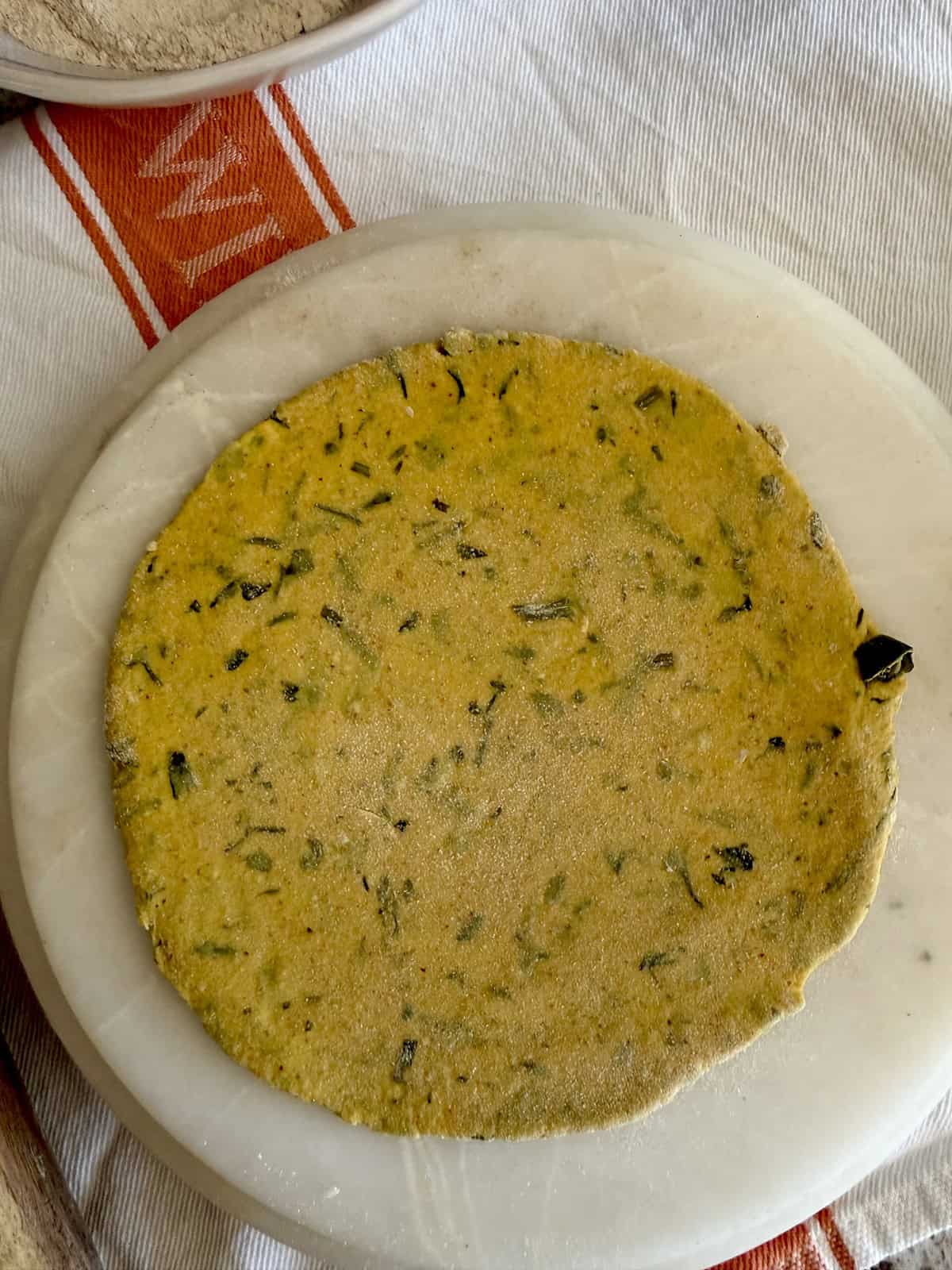 A rolled out high protein tofu thepla on a marble rolling surface.