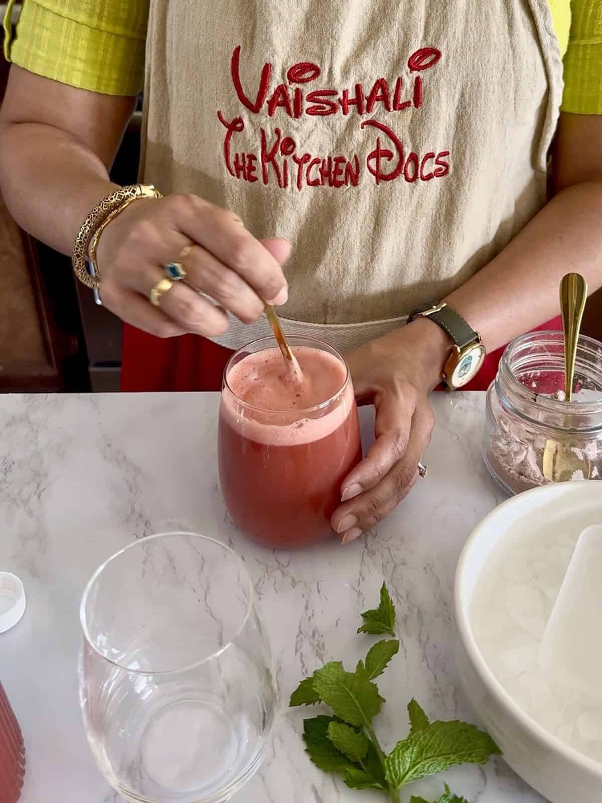 Stirring Pink Himalayan salt into a cup of chilled watermelon mint spritzer.
