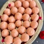 Close-up of rose coconut ladoos on a decorative silver platter.
