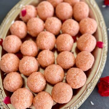 Close-up of rose coconut ladoos on a decorative silver platter.
