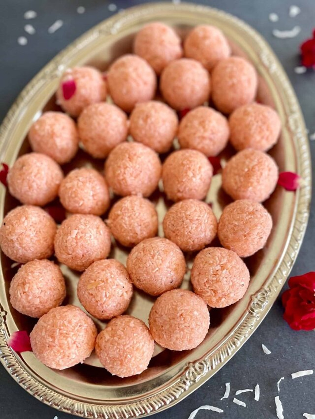 Close-up of rose coconut ladoos on a decorative silver platter.