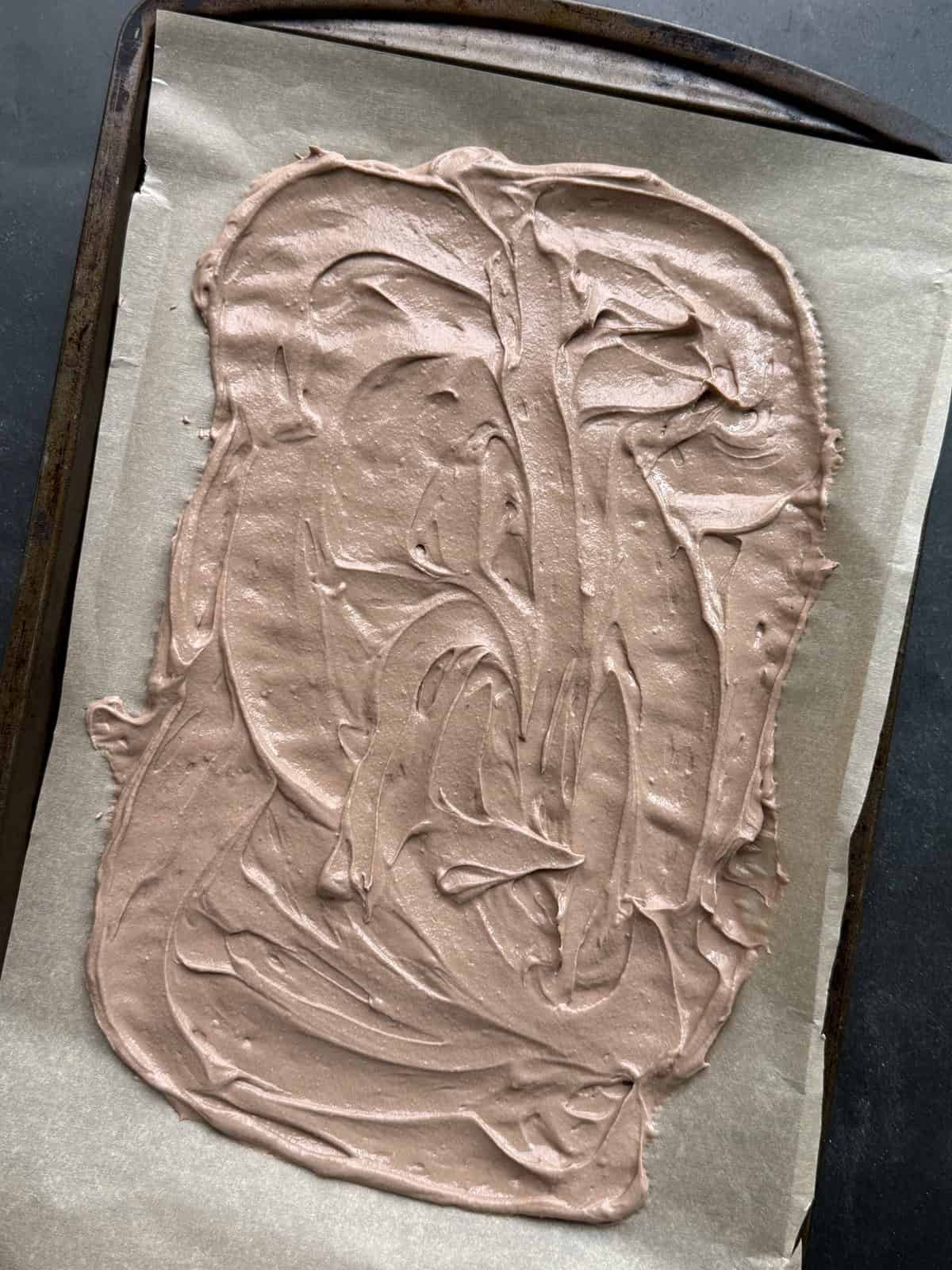 High protein chocolate yogurt base spread on a parchment lined cookie sheet.