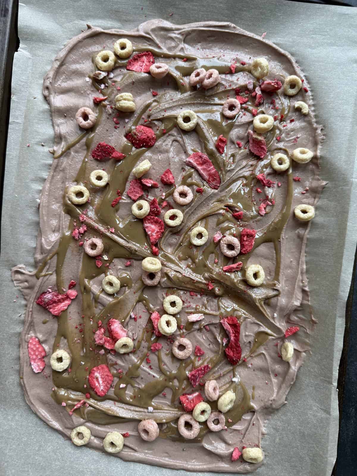 Adding crispy cereal onto chocolate SunButter yogurt bark before freezing.