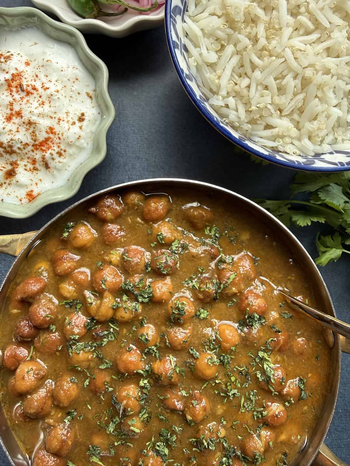 Punjabi kala chana curry, black chickpea curry in a onion-tomato masala served in a stainless steel bowl with basmati rice on the side.
