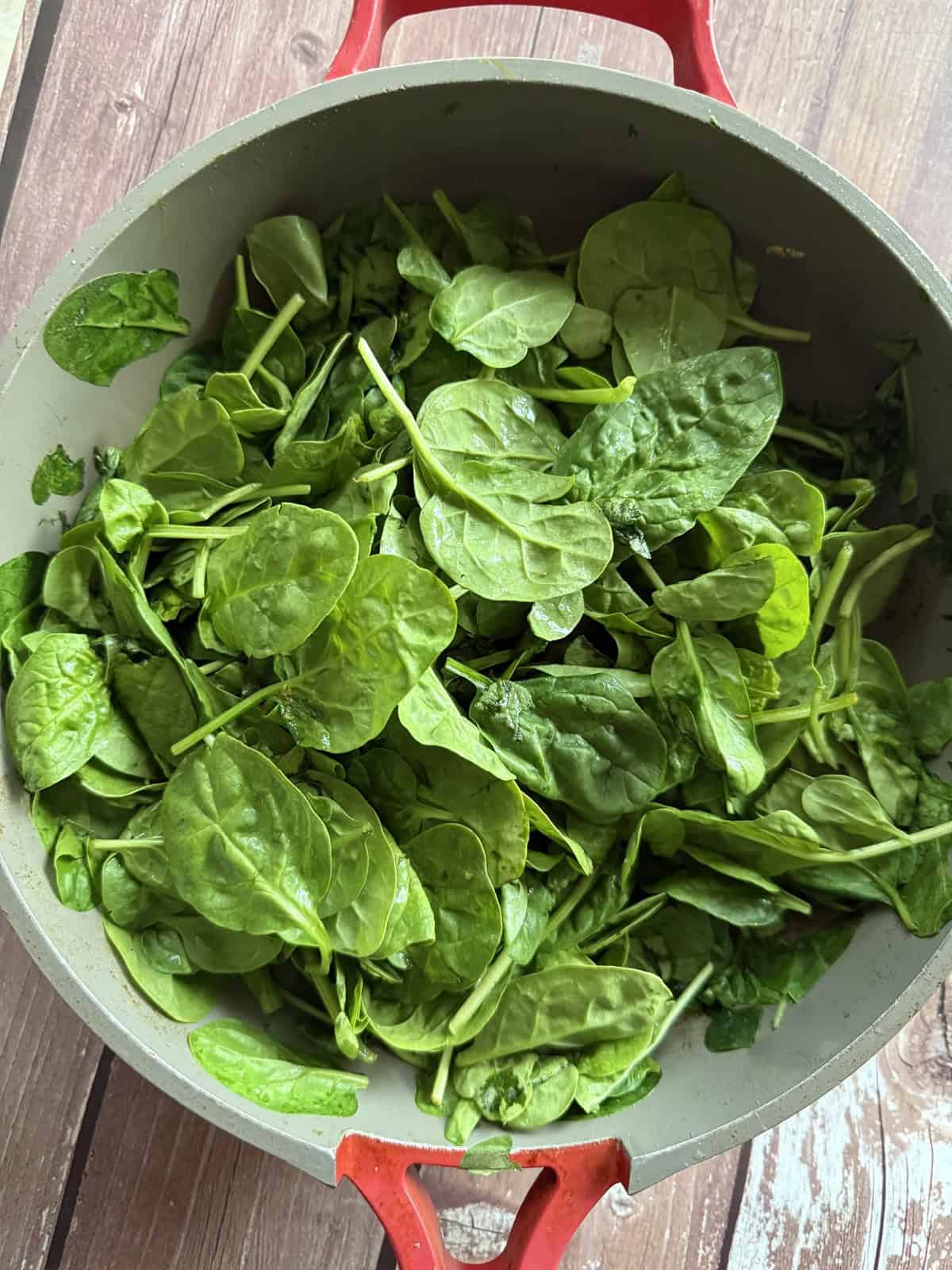 Spinach leaves in a ceramic non-stick pan.